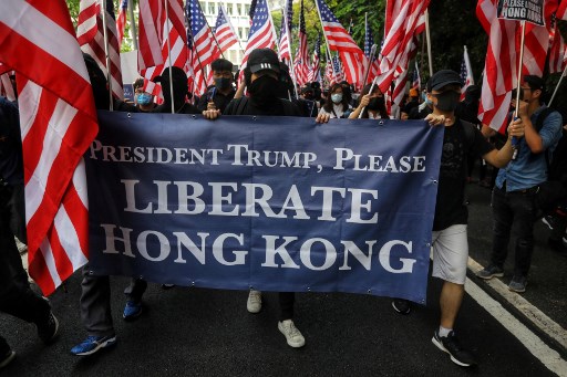 Protesters hold a banner and wave US national flags as they march from Chater Garden to the US consulate in Hong Kong on September 8, 2019, to call on the US to pressure Beijing to meet their demands and for Congress to pass a recently proposed bill that expresses support for the protest movement. – Pro-democracy activists planned to rally outside the US consulate in Hong Kong on September 8 as the they try to keep international pressure on Beijing following three months of huge, sometimes violent, protests. (Photo by Vivek Prakash / AFP)