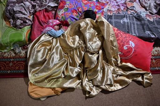 This picture taken on September 14, 2019 shows Indonesian children resting at a clinic, used as a tempotary shelter, after they fled their homes due to the haze in Pekanbaru. (Photo by ADEK BERRY / AFP)