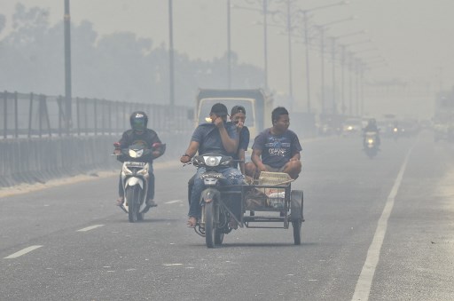 Motorists make their way along a street in Kampar, Riau on September 17, 2019 which is covered in thick haze. – Indonesia is battling forest fires causing toxic haze across southeast Asia with aircraft, artificial rain and even prayer, President Joko Widodo said during a visit to a hard-hit area. (Photo by Wahyudi / AFP)