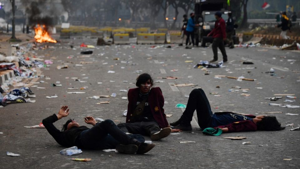 Student protesters react after police fired tear gas into the area during a demonstration against the government’s proposed change in its criminal code laws and plans to weaken the anti-corruption commission, outside the parliament building in Jakarta on September 24, 2019. (Photo by ADEK BERRY / AFP)