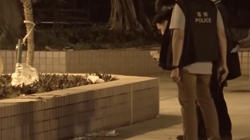 Police investigate the scene outside a housing estate in Ap Lei Chau after someone poured corrosive liquid and threw glass bottles at people singing protest songs outside. Screengrab via Facebook/RTHK.