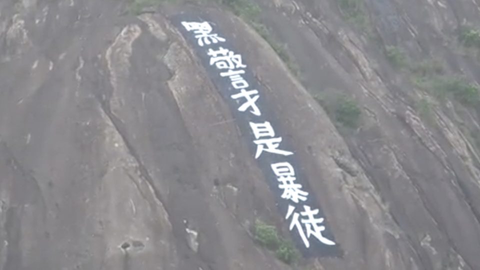 A banner reading ‘dirty cops are rioters’ was unfurled on the side of Devil’s Peak last night. Screengrab via Apple Daily video.