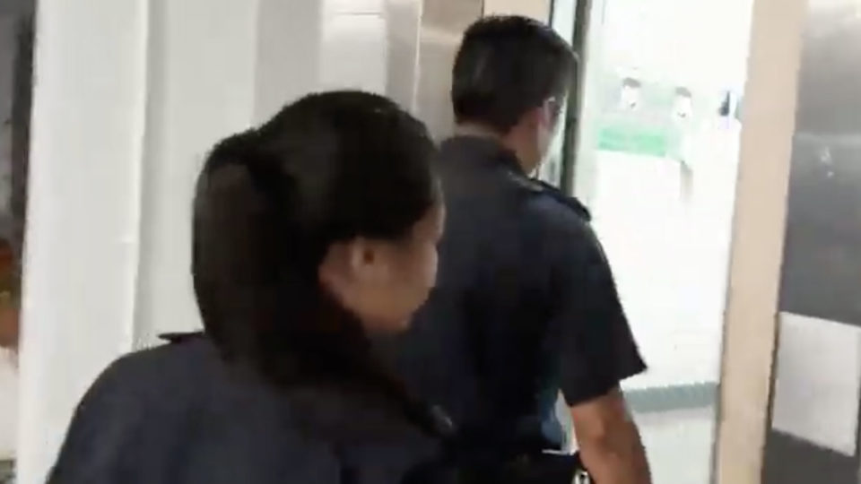 Police officers entering a lift as a woman harasses them.