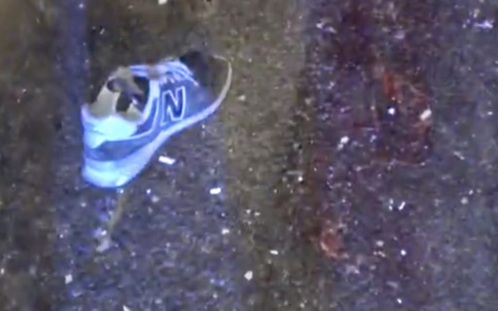 A left foot sneaker on the road next to a patch of bloog on Tsing Kwai Highway, the spot where a truck driver lost part of his left leg. Screengrab via Apple Daily video.
