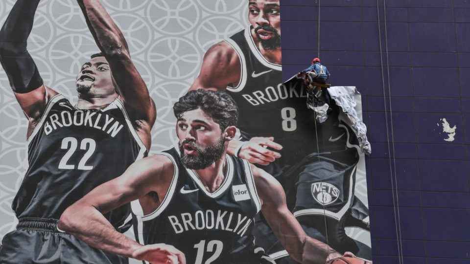 A worker removes a promotional banner from a building for the National Basketball Association (NBA) October 10 preseason game in China between the Brooklyn Nets and the Los Angeles Lakers in Shanghai on October 9, 2019. – Chinese state media slammed the NBA for an “about-face” on October 9 after the body said it would not apologise for a tweet by the Houston Rockets General Manager supporting pro-democracy protests in Hong Kong. (Photo by HECTOR RETAMAL / AFP)