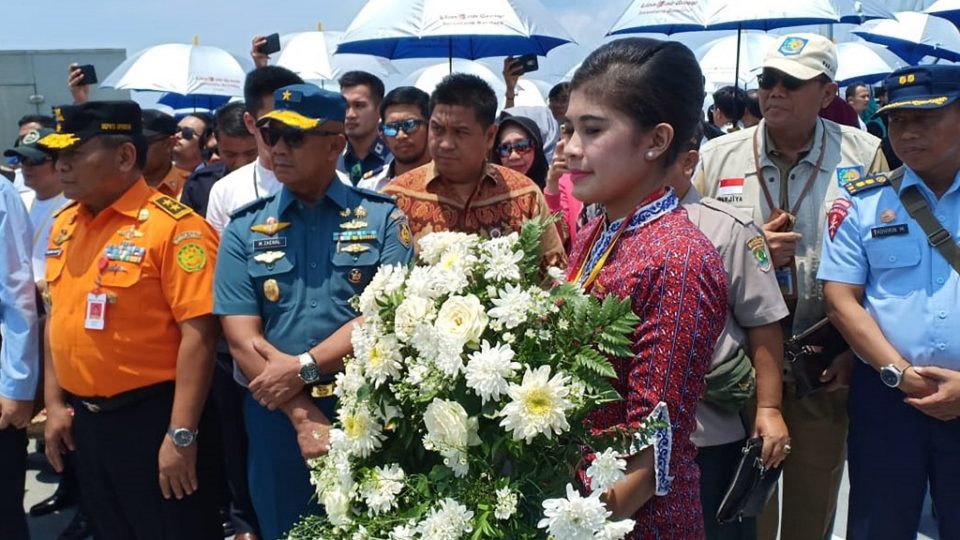 A Lion Air flight attendant carries a wreath of flowers onboard a navy ship on the Java sea on October 29, 2019, during a ceremony for victims of a Lion Air plane crash in 2018. – Grieving relatives tossed flowers into the sea on October 29 where an Indonesian Lion Air jet crashed a year ago, killing all 189 aboard, after a final accident report pointed to design flaws as a key factor in the disaster. (Photo by DANANG / AFP)