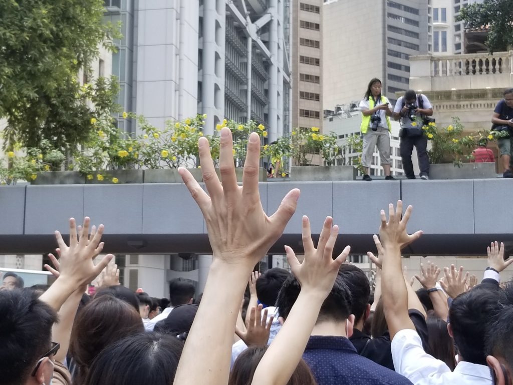 Protesters hold up five fingers to represent the slogan 'five key demands, not one less'. Photo by Vicky Wong.