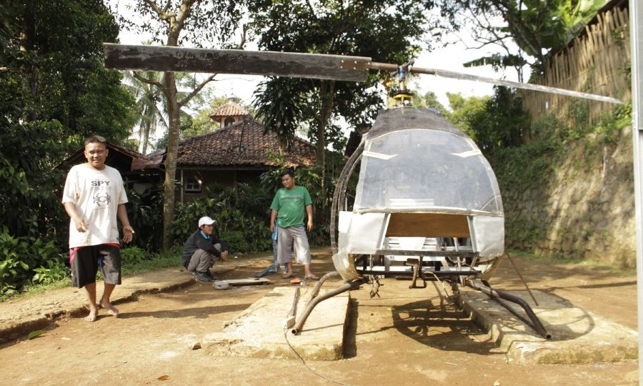 This picture taken on November 17, 2019 shows Jujun Junaedi (L) working on his homemade helicopter in his backyard in Sukabumi. – Jujun Junaedi spends days off in the backyard tinkering with the do-it-yourself chopper — guided by online instructional videos — as he dreams of flying over jams in his hometown Sukabumi. (Photo by Wulung WIDARBA / AFP)