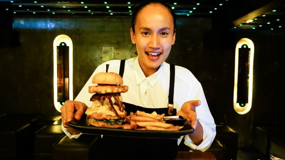 Kanitcha “Nam” Boonkhun shows off her burger and fries, signature menu served at Stryke Bangkok