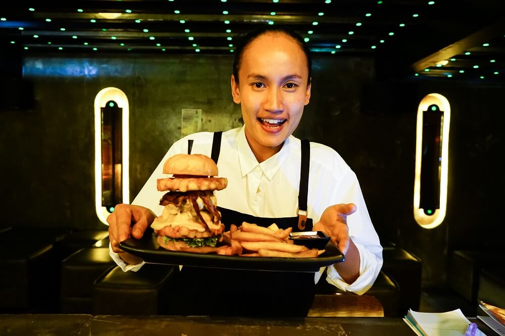 Kanitcha “Nam” Boonkhun shows off her burger and fries, signature menu served at Stryke Bangkok