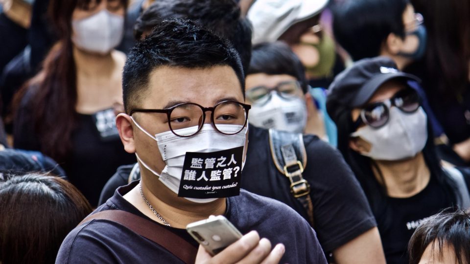 Protester wearing a mask with the words in Latin ‘who will watch the watchmen’ at an anti-mask law rally on October 20, 2019. Photo by Vicky Wong.