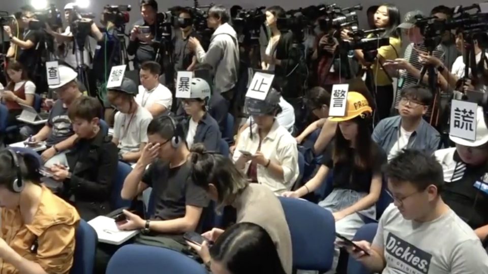 Six reporters from local news outlets staged a silent protest at a police press briefing this afternoon. Screengrab via Facebook video.