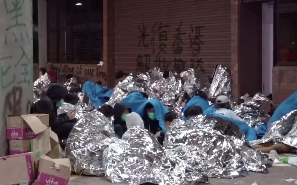 Protesters who've emerged from Polytechnic University covered in emergency blankets after surrendering. Screengrab via Apple Daily video.