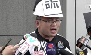 Stand News journalist Ronson Chan speaks to reporters after he and five other journalists staged a silent protest during a police press briefing. Screengrab via Facebook/RTHK.
