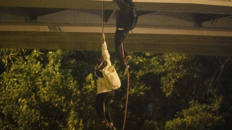 Protesters lower themselves down a rope from a bridge to a highway to escape from Hong Kong Polytechnic University campus and from police on Nov. 18, 2019. Photo via AFP.