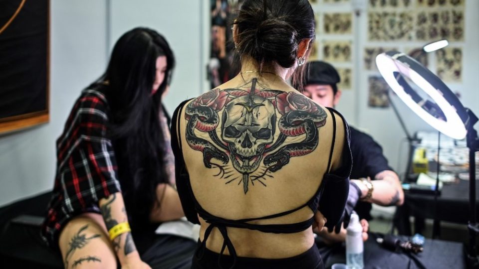 A woman with tattoo watches an artist worksing during the International Malaysia Tattoo Expo in Kuala Lumpur on November 29, 2019. – The international tattoo expo is held for the first ime in Kuala Lumpur celebrating that art of tattoo and gathering over a hundred tattoo artists from 40 countries. (Photo by Mohd RASFAN / AFP)