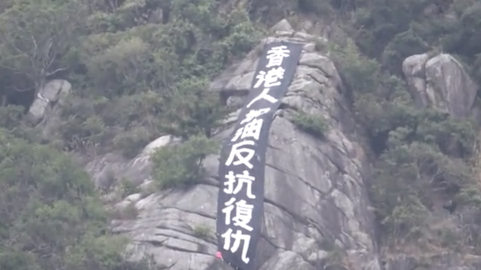 A black banner on Beacon Hill reads “Hongkongers add oil, resist, avenge.” Screengrab via Apple Daily video.
