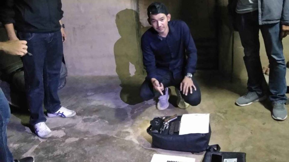 
Danusorn Noomcharoen points to weapons and ammunition early Wednesday morning inside his Phetchaburi province home, where he was arrested on suspicion of killing his ex-wife inside a Bangkok shopping mall. 
