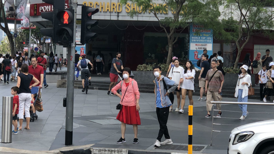 Pedestrians wearing masks cross Singapore’s Orchard Road. Photo: Coconuts Media