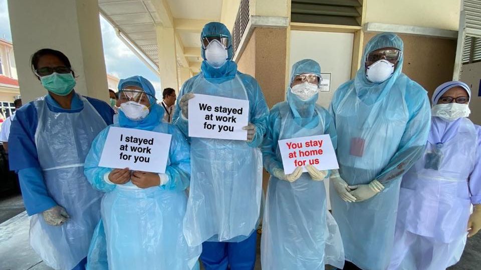 Medical workers in Malaysia hold up printed messages telling everyone to stay home, in a photo dated March 20. Photo: Noor Hisham Abdullah/Facebook