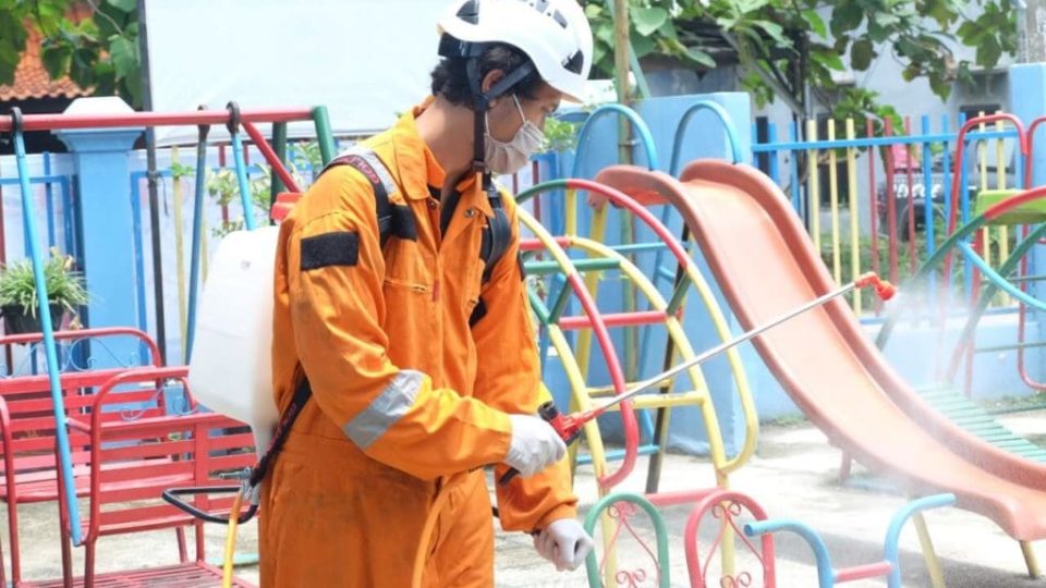 A worker disinfecting a children’s playground in Indonesia. Photo: Dompet Dhuafa