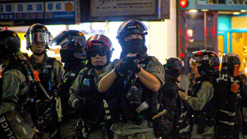 A riot policeman brandishes a tear gas grenade launcher at protesters in Mong Kong on Saturday night. Photo by Tommy Walker.