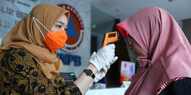 An employee at the National Disaster Mitigation Agency (BNPB) having her temperature scanned as a precaution against COVID-19. Photo: BNPB