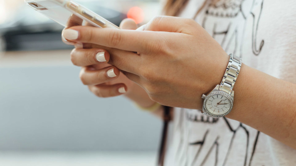 A woman holds a smartphone. Photo: Paul Hanaoka