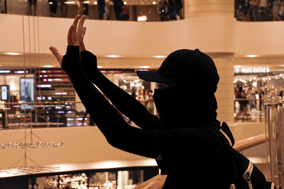 A black-clad protester holds up her hands to make the 'Five demands, not one more' gesture. Photo: Tommy Walker
