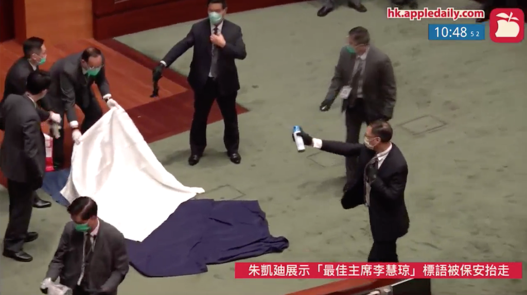 Security guards cover the bag and spray air freshener. Photo: Apple Daily live feed