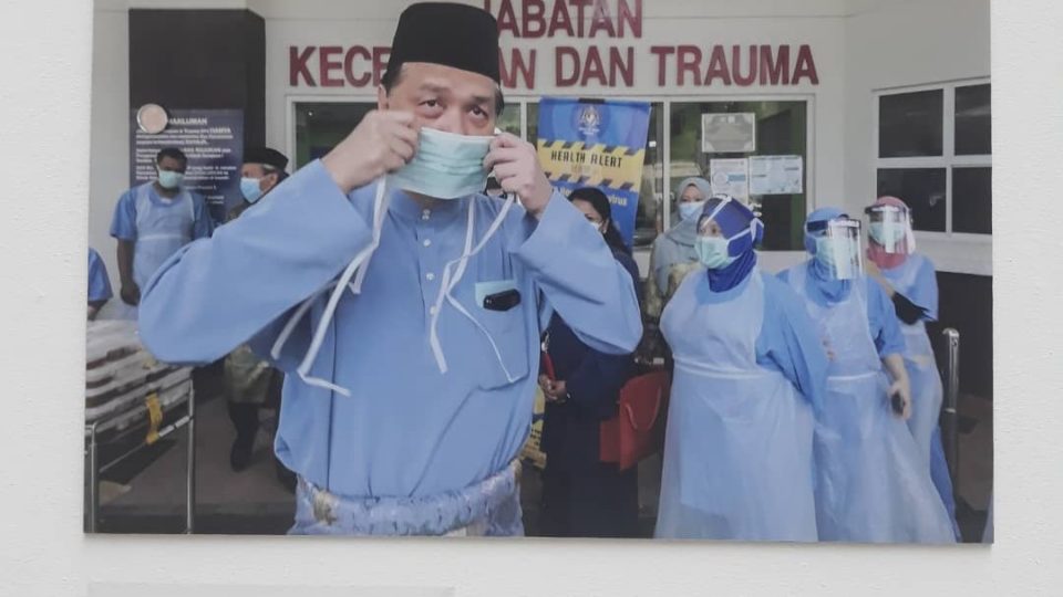 Health DG Noor Hisham Abdullah wears a mask on Hari Raya among photos on display. Original photo by Harry Salzman. Photo: Coconuts KL
