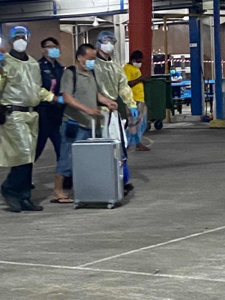 Migrant worker escorted out of the dormitory with his luggage. Photo: Singapore Eye/Facebook