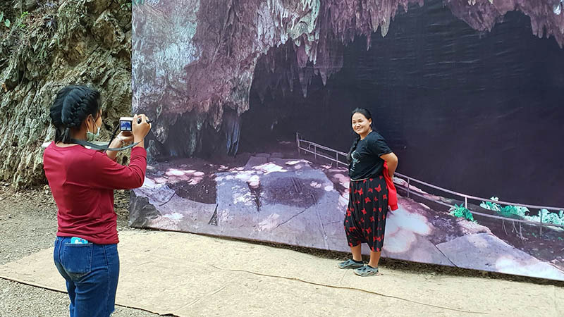 Tourists take photos in front of a backdrop showing the entrance to Tham Luang a few steps from the real thing in a January 2019 file photo. Photo: Coconuts