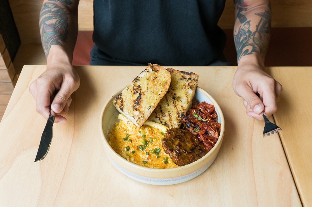 A customizable 'breakfast bowl' featuring grilled focaccia, scrambled egg, sai-ua patty and roasted tomatoes.
