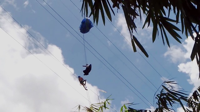 Indonesian paraglider Hans Mawikere hanging some 100 feet off the ground after his chute got tangled in power lines. Photo: PLN