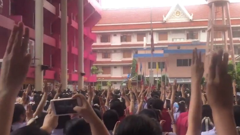 Students raise three fingers while the national anthem is sung Monday morning at the Satri Wat Absorn Sawan School in Bangkok. Photo: @Memokichan / Twitter