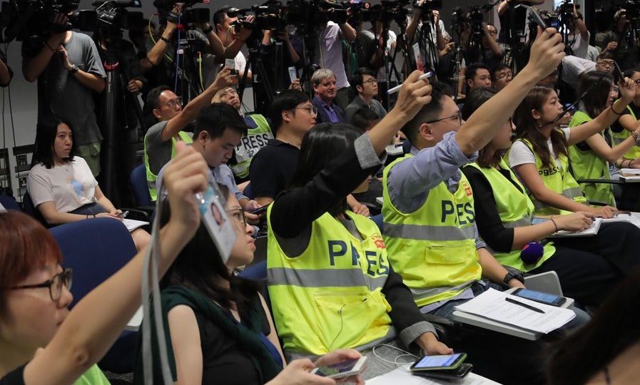 Hong Kong journalists raise their press passes in a show of protest against police’s obstruction of reporting during a press conference on Aug. 12, 2019. Photo via Apple Daily