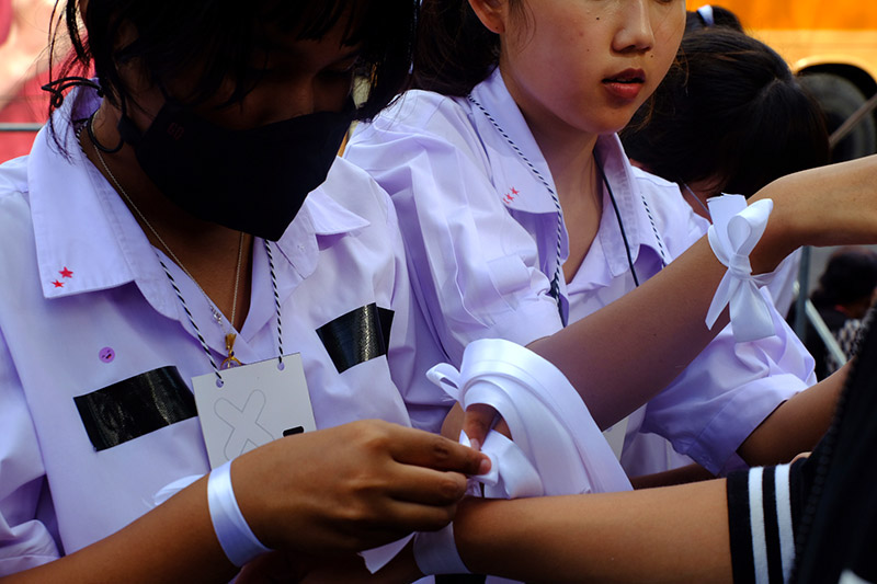 Students tie symbolic white ribbons showing their support for restoring democracy. Photo: Krittin Kitsahawong 