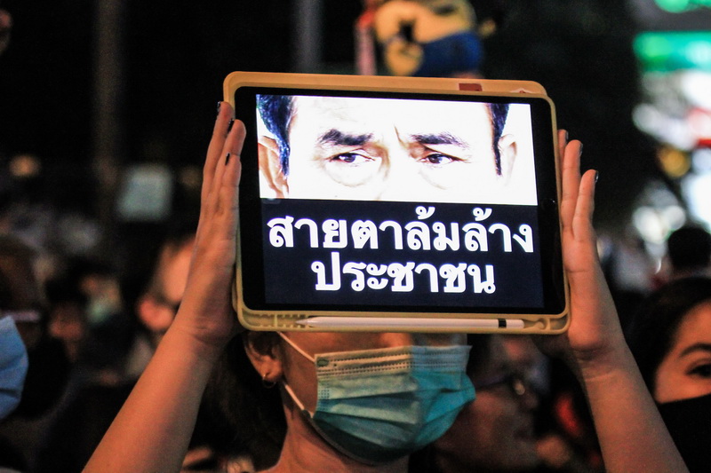 ‘Demolishing-the-people stare,’ reads an image of Prime Minister Gen. Prayuth Chan-o-cha on an iPad held by a protester at a Monday evening rally in Bangkok. Photo: Coconuts