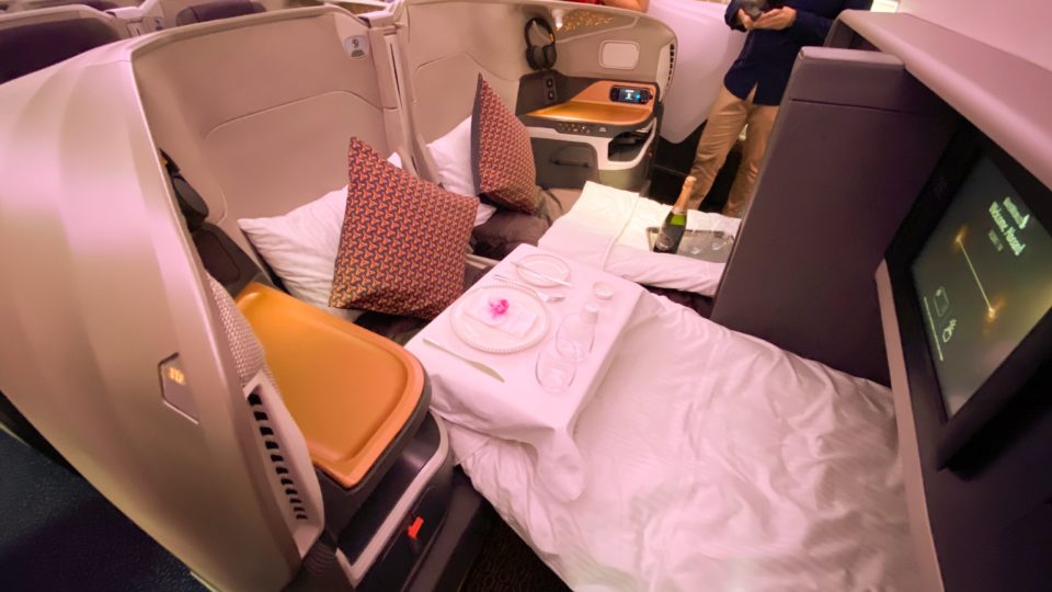 A business class seat with bed extended and dining table set. Photo: Coconuts
