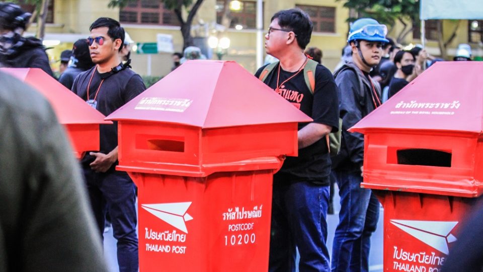 Protesters push makeshift mailboxes bearing the palace’s postal code Sunday from the Democracy Monument to the Grand Palace. The march culminated in thousands of protesters submitting letters addressed to King Vajiralongkorn. Photo: Coconuts 
