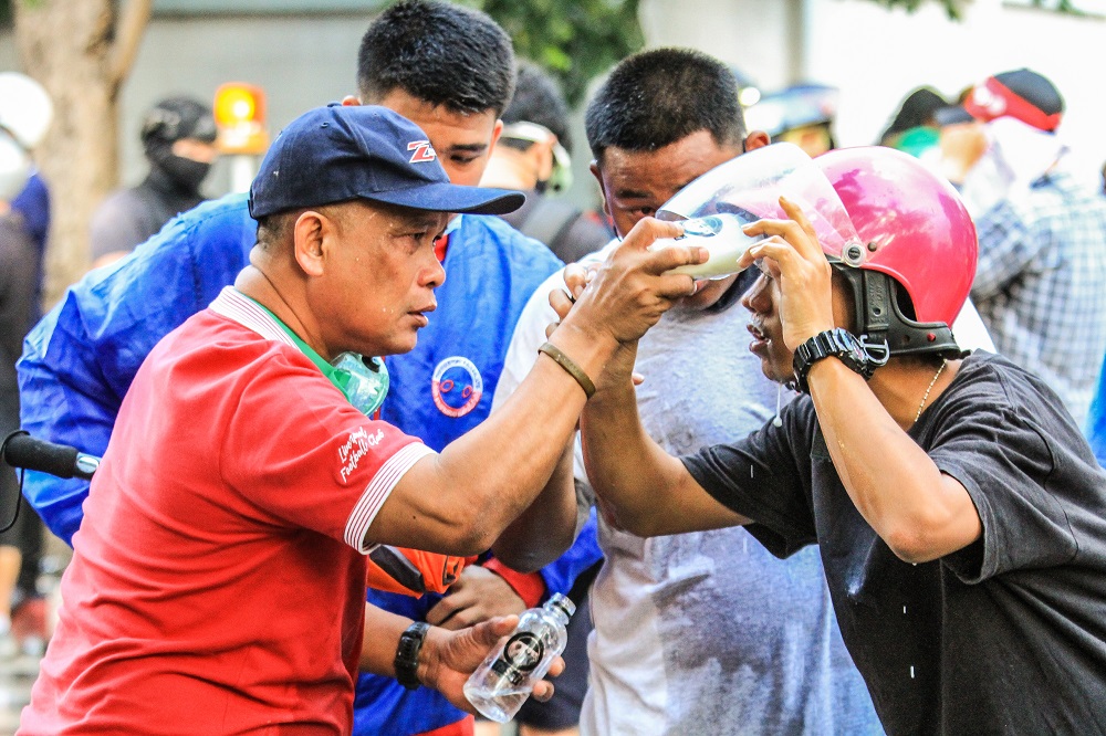 Protesters use water, saline and milk to rinse their eyes. Photo: Coconuts