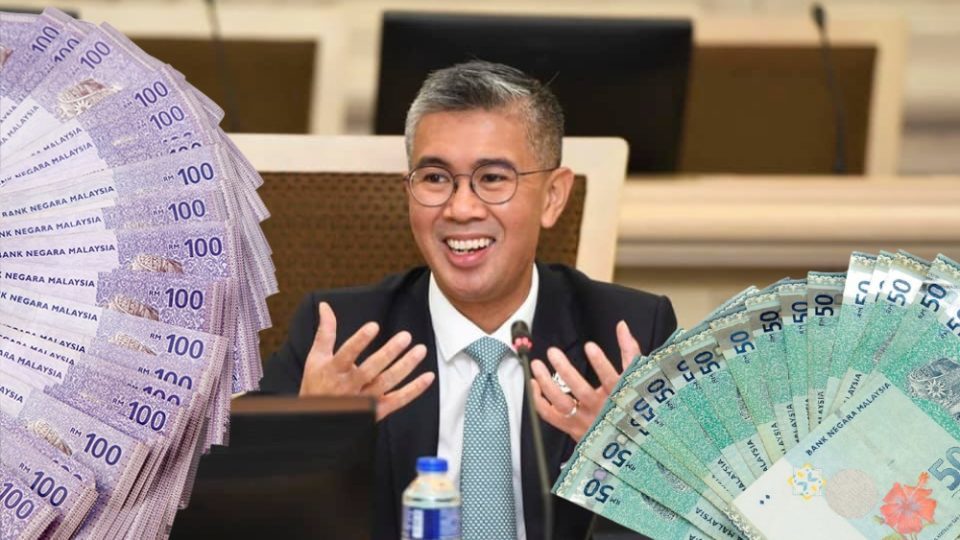 Zafrul Aziz speaks to people in his office, surrounded by graphics of RM100 and RM50. Photo: Coconuts
