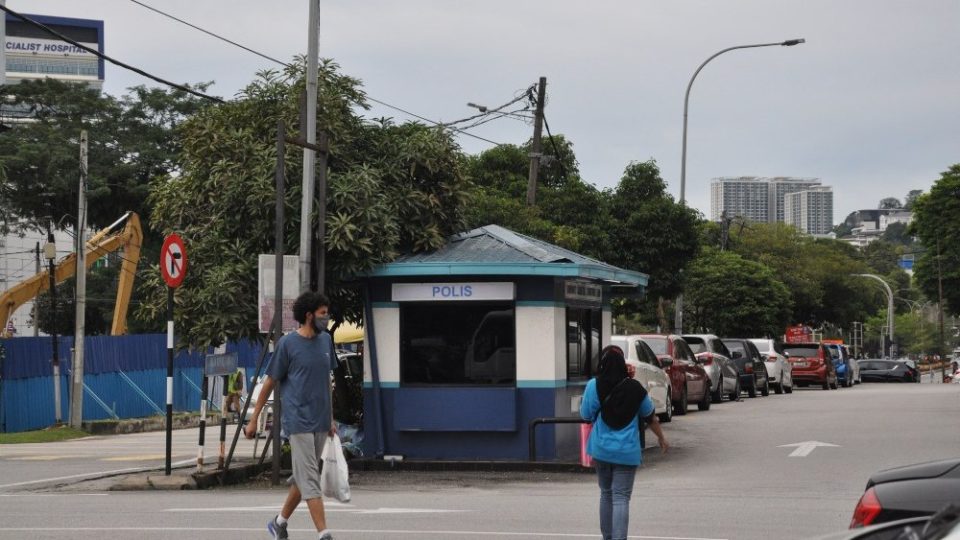 People walking near the police bit base in Jalan Ampang Utama. Photo: Coconuts
