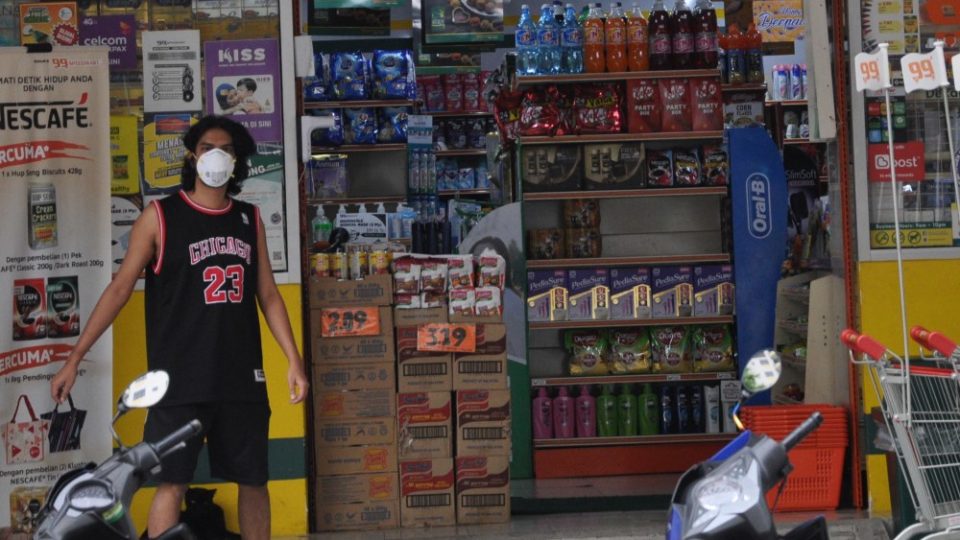 A masked man stands in front of a grocery store in KL. Photo: Coconuts KL
