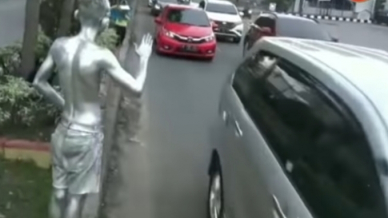 A “silver man” street performer asking for donations from passing cars on a street in Indonesia (Illustration only). Photo: Istimewa