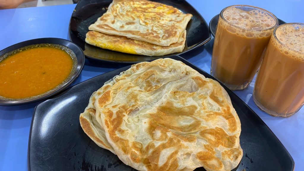 Plates of egg and plain prata, glasses of teh tarik, and a bowl of curry. Photo Carolyn Teo/Coconuts