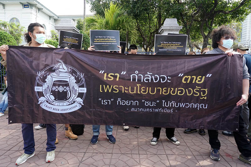 “We are dying because of the government policies. We want to ‘win’ with you too,” reads a banner held this morning by members of the Craft Beer Association outside the COVID-19 task force offices at the Interior Ministry in Bangkok. Photo: Coconuts