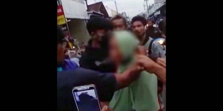 A middle aged woman accused of stealing IDR100K being roughed up by a mob in Indonesia. Photo: Video screengrab