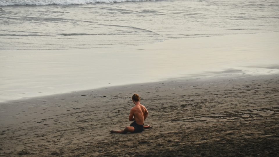 A man stretches on a beach in Bali. Photo: Unsplash